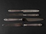 four knives and a knife holder on a black surface