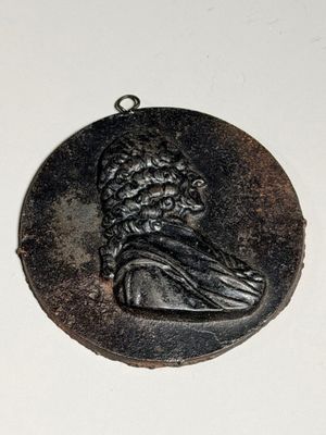 un médaillon noir sur lequel figure le portrait d'un homme