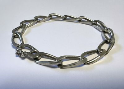 gros plan d'un bracelet métallique sur une surface blanche