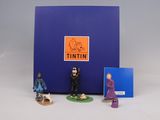 three figurines of people standing in front of a blue box