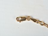a gold chain with a heart on it on a white surface