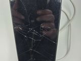 a broken cell phone sitting on a table with a cord