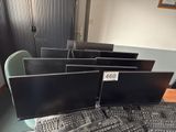 a lot of computer monitors and keyboards on the desk