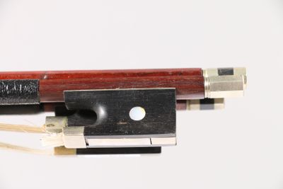 un archet de violon et un repose-archet posés sur une surface blanche