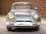 a silver car that is parked in front of a brick wall