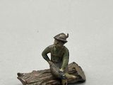 figurine représentant un homme assis sur une bûche avec un chien