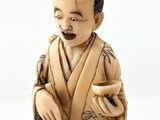 a statue of a man sitting on a stool holding a cup