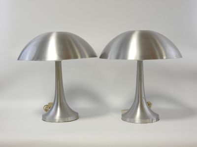 deux lampes argentées posées sur une surface blanche, avec un fond blanc