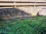 une chaise en métal rouillée posée dans l'herbe près d'un mur