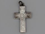 une vieille croix en argent, ornée d'une croix, posée sur une surface grise