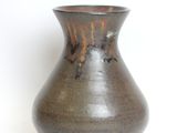 a brown vase that is sitting on a white surface