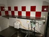un évier dans une petite cuisine dont les murs sont carrelés de rouge et de blanc