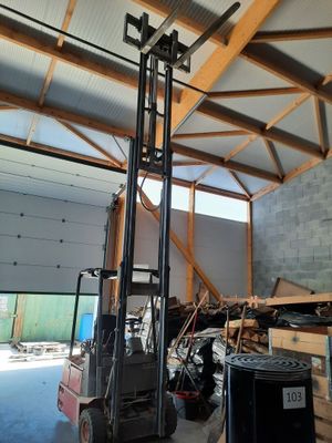 a forklift in a warehouse with a lot of junk