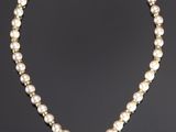 un collier en perles et en or orné d'un pendentif en pierre bleue