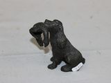 figurine représentant un chien noir tenant une médaille dans la gueule