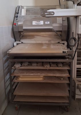 several trays of food sit on a metal rack in a kitchen