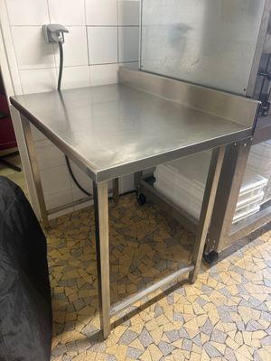 une table en acier inoxydable avec une chaise noire devant