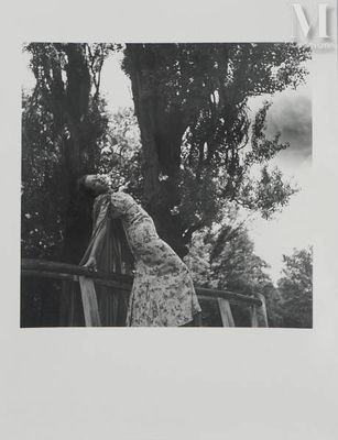 photographie en noir et blanc d'une femme appuyée contre une clôture