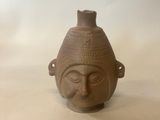a small brown vase with a face on it