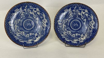 two blue and white plates with designs on them sitting on a table