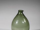 a green glass vase sitting on a white surface
