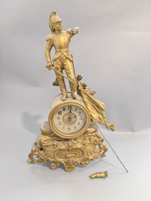 une horloge en or surmontée d'une statue d'homme