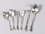 five silver spoons and two silver spoons on a white surface