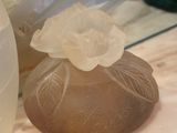 a glass vase with a flower on it next to a rock
