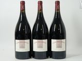trois bouteilles de vin rouge sont alignées sur une surface blanche