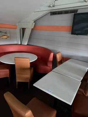 tables and chairs in a restaurant with a flat screen tv on the wall