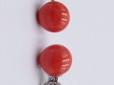three pairs of red coral and diamond earrings on a white surface