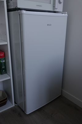 a small white refrigerator in the corner of a room