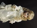 a doll with blonde hair wearing a white dress