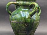 a green vase with two handles on a table