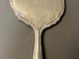 silver plated hand held mirror on a black surface
