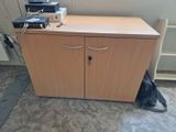 une armoire en bois à deux portes, sur laquelle est posé un ordinateur