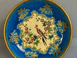 une assiette bleue ornée d'un oiseau et de fleurs