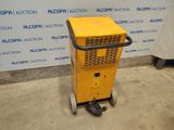 a yellow machine sitting on top of a cement floor next to a wall