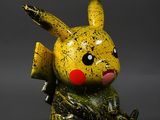 figurine de pikachu jaune et noir assise sur une surface grise