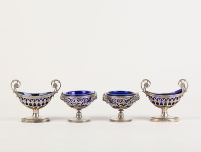 trois plats en verre argenté et bleu posés sur des socles, disposés sur une surface blanche