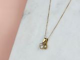 un collier en or avec un pendentif en diamant posé sur une surface en marbre