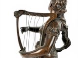 bronze statue of a woman holding a harp on a white background