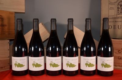six bottles of red wine are lined up on a table