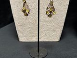 pair of yellow and green earrings on display on a stand
