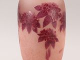 a pink vase with purple flowers on it on a white background