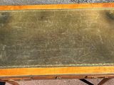 a small wooden table with a green leather top