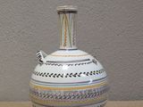 a white vase sitting on a table next to a wall