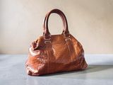un sac à main en cuir marron posé sur une table près d'un mur