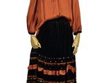 un mannequin portant une robe noire et orange, posé sur un socle