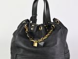 sac à main en cuir noir avec des anses en chaîne dorée, sur fond blanc
